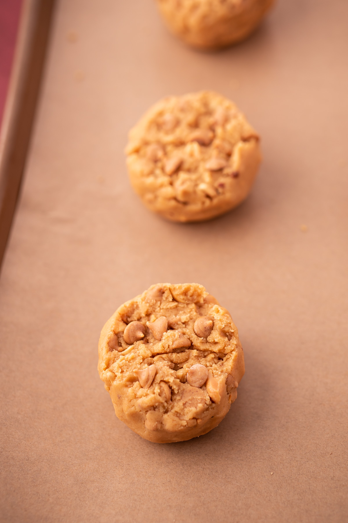 Triple Peanut Butter Cookie Dough balls on a baking sheet lined with parchment paper.