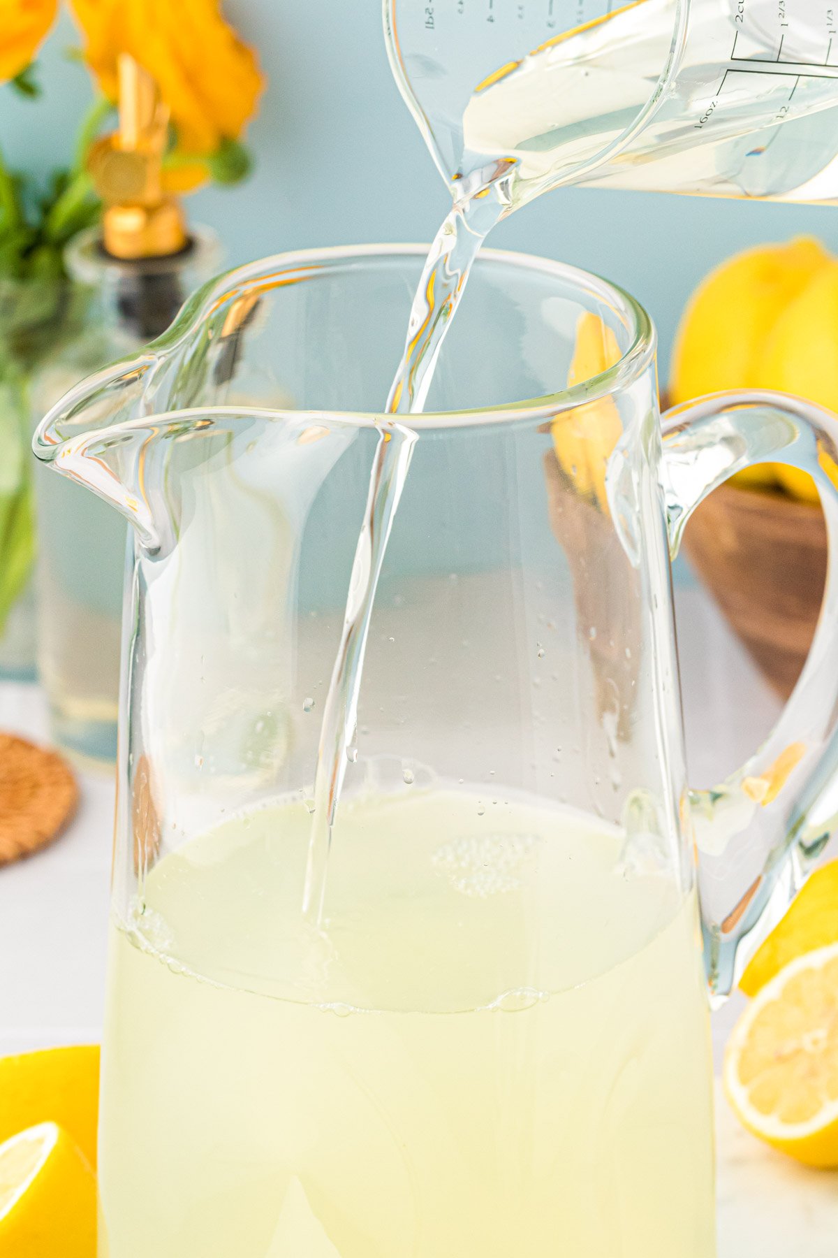 Water being poured into a glass pitcher to make lemonade.
