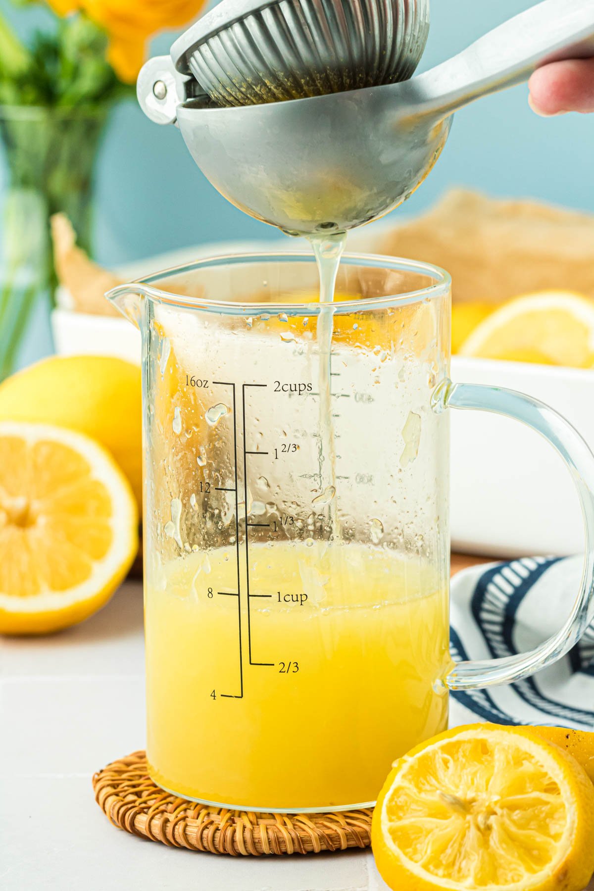 Lemons being pressed for juice into a measuring cup.