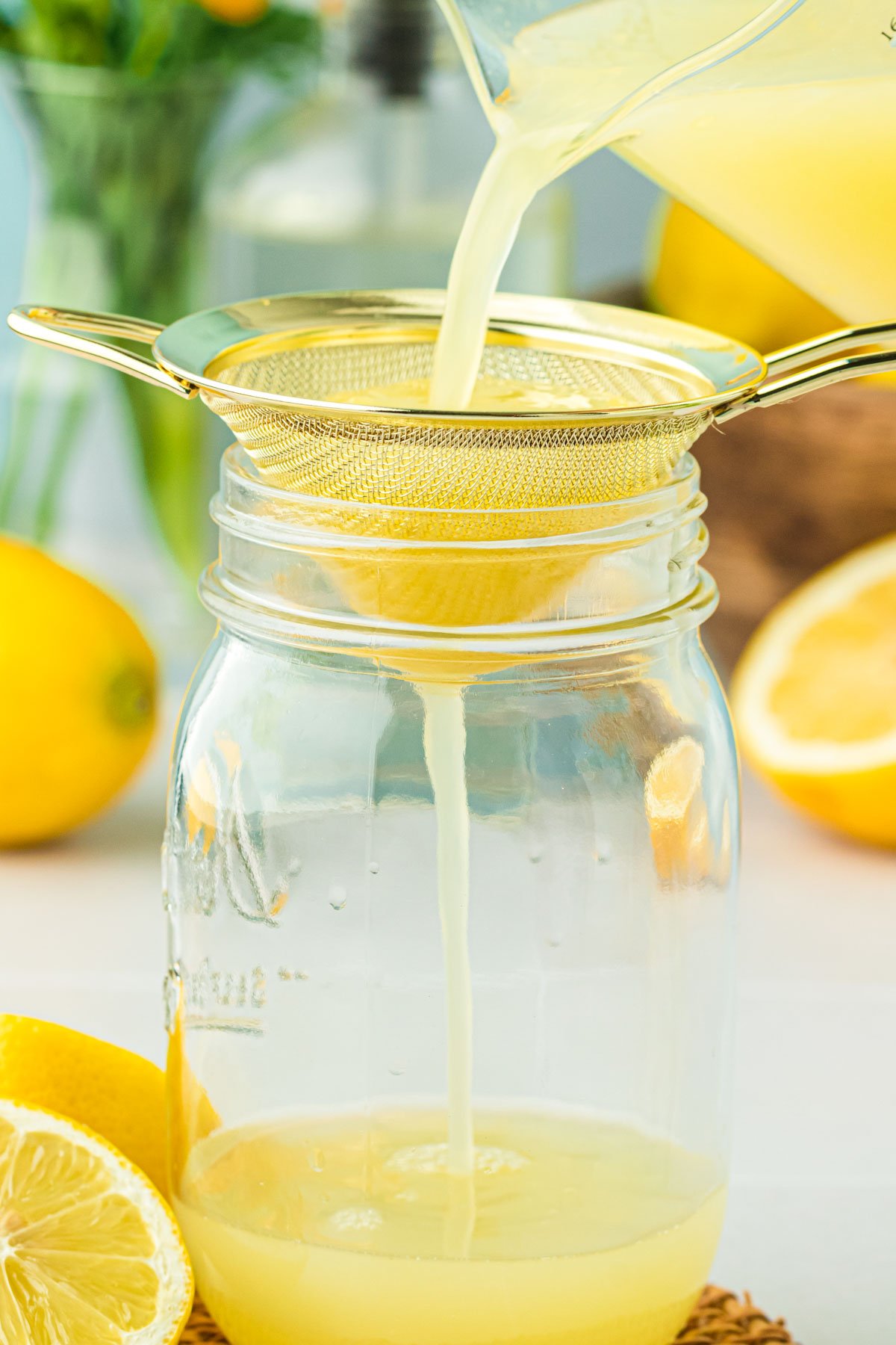 Lemon juice being poured through a fine-mesh sieve.