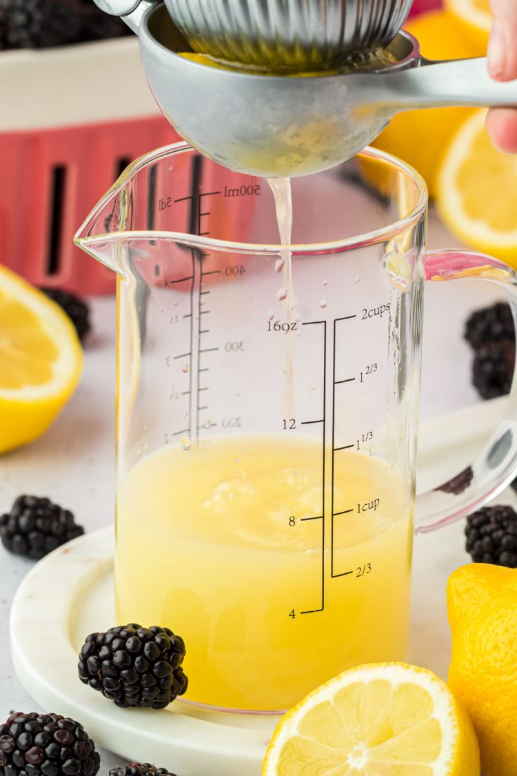 Lemons being squeezed into a measuring cup.