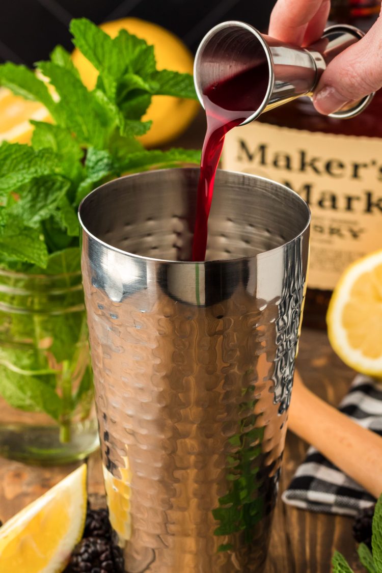 Blackberry simple syrup being poured into a silver cocktail shaker.