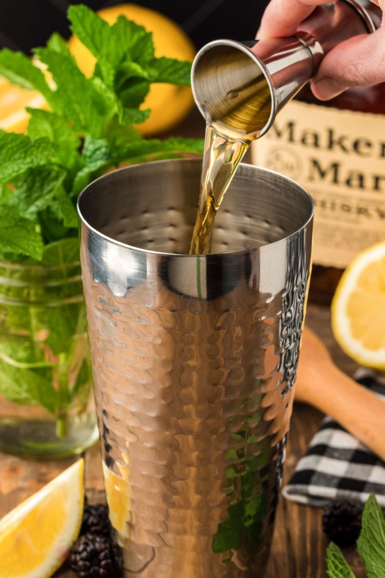 Whiskey being poured into a cocktail shaker.