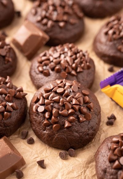 Caramel stuffed chocolate cookies topped with mini chocolate chip on parchment paper.