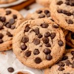 Close up of chocolate chip cookies with cinnamon sugar coating in a pile on a table.