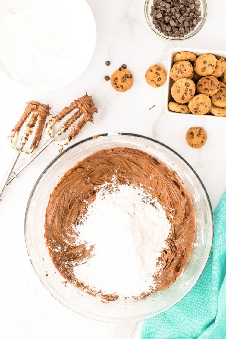 Powdered sugar being added to chocolate and butter to make frosting.