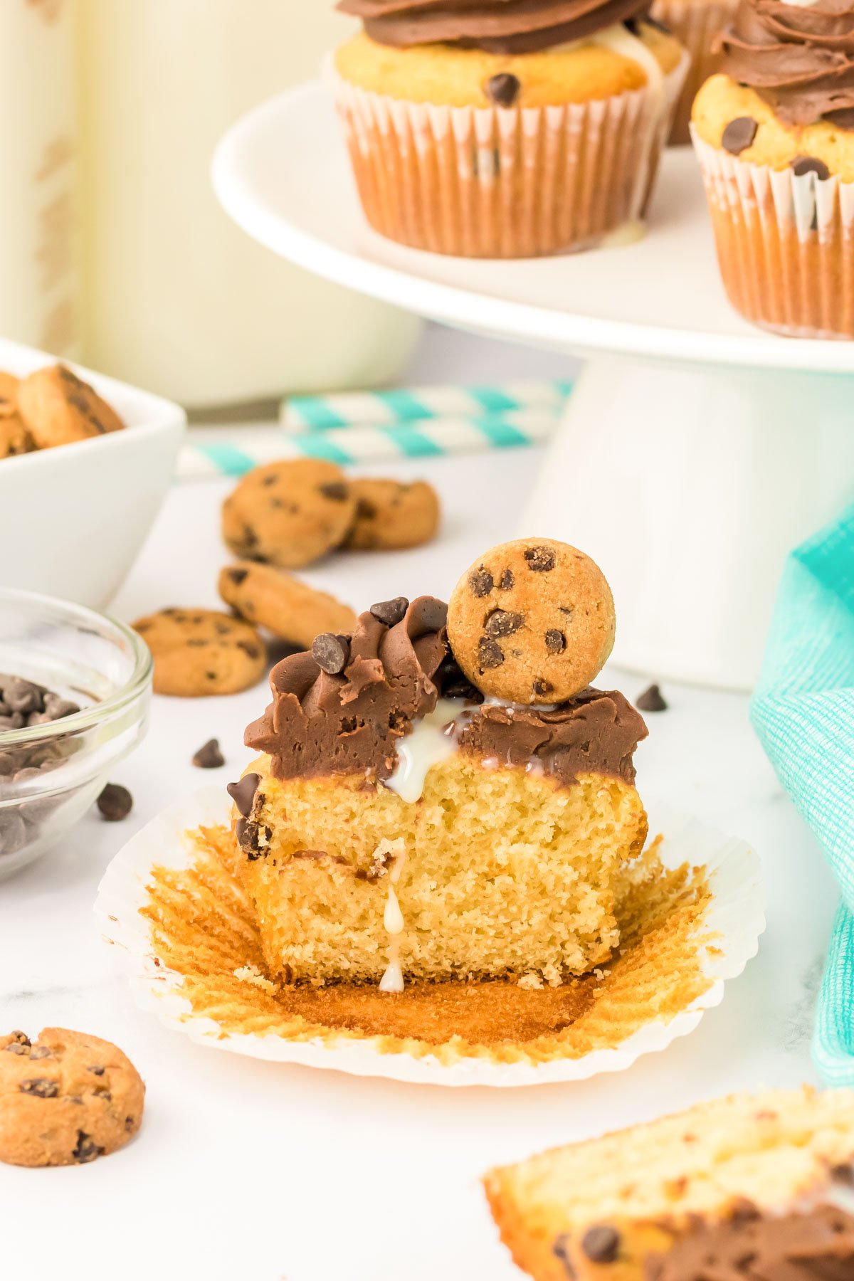 Milk and cookies cupcakes on a white table. One has been sliced in half. 