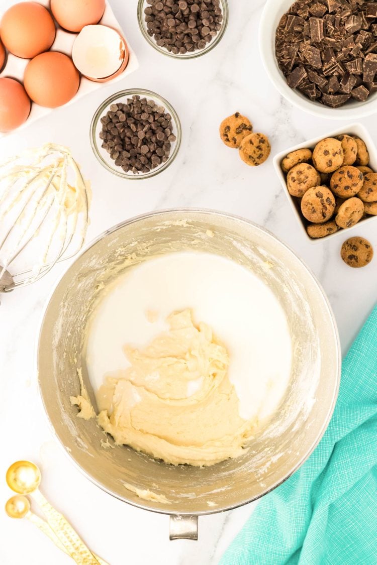 Milk being added to a bowl with cake batter.