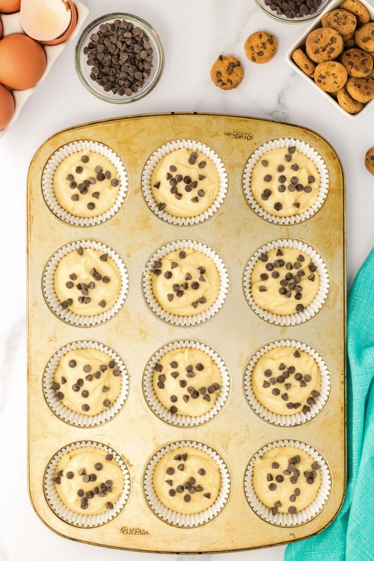 A cupcake pan filled with batter to make chocolate chip cupcakes.