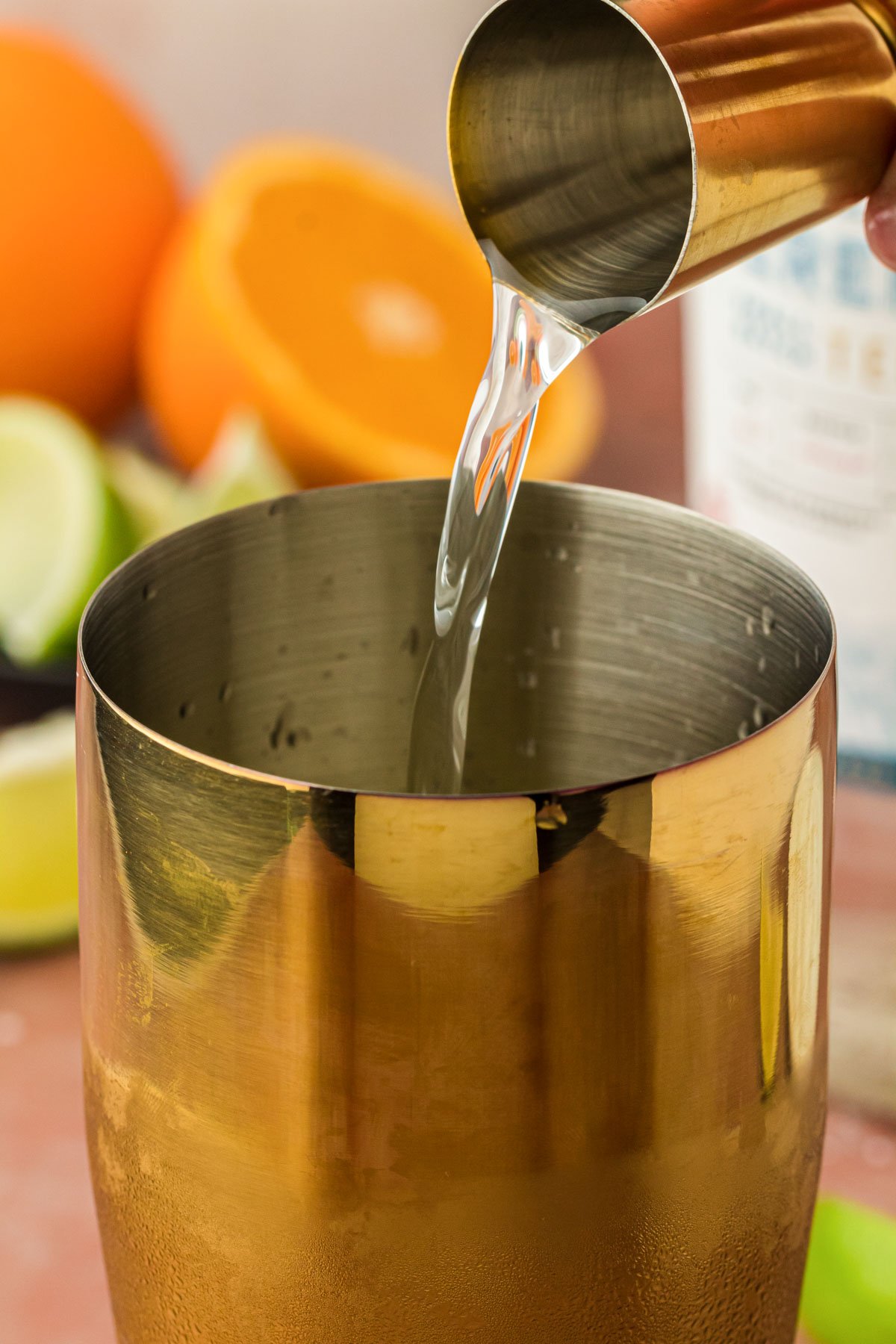 Tequila being added to a cocktail shaker.