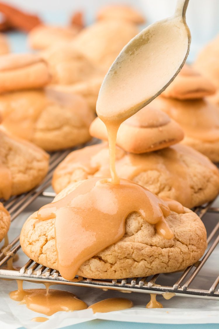 Brown sugar icing being spooned over the top of a brown sugar cookie.