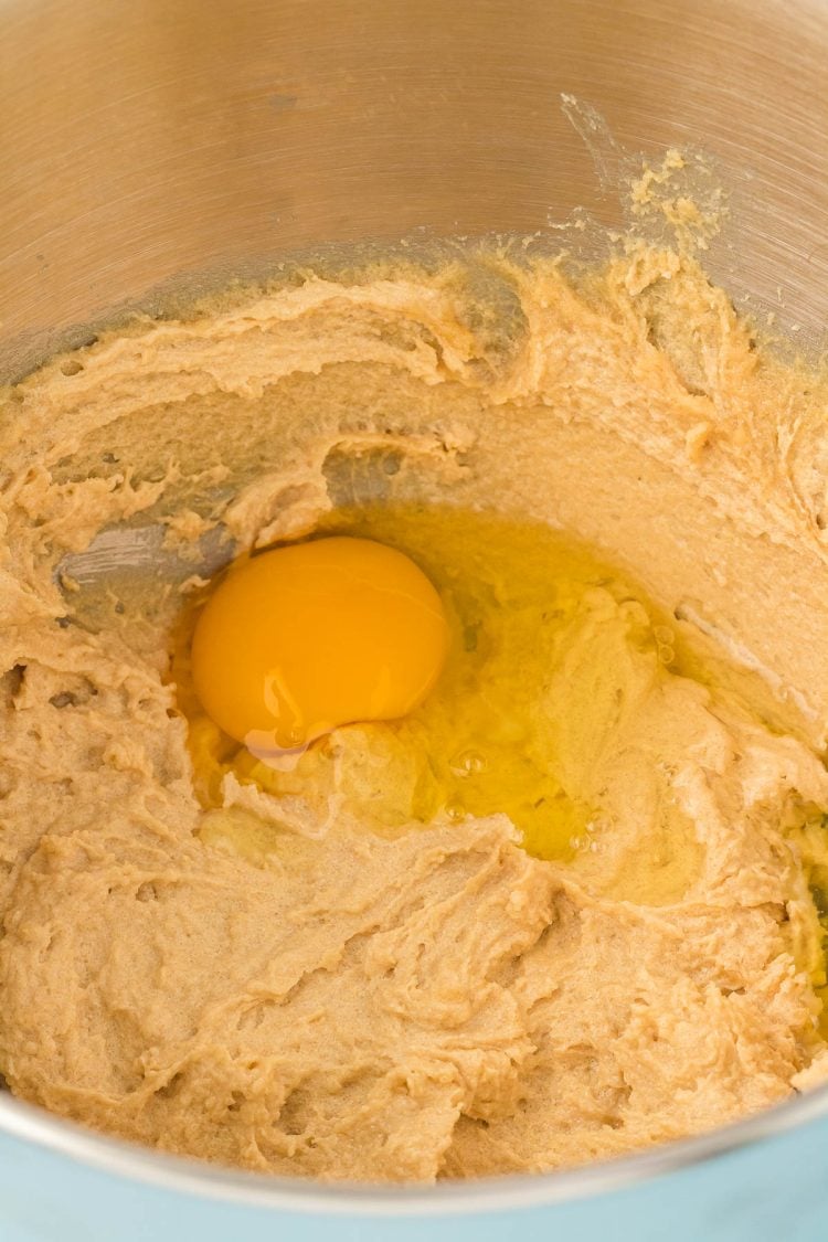 Egg being added to butter and sugar to make cookie dough.