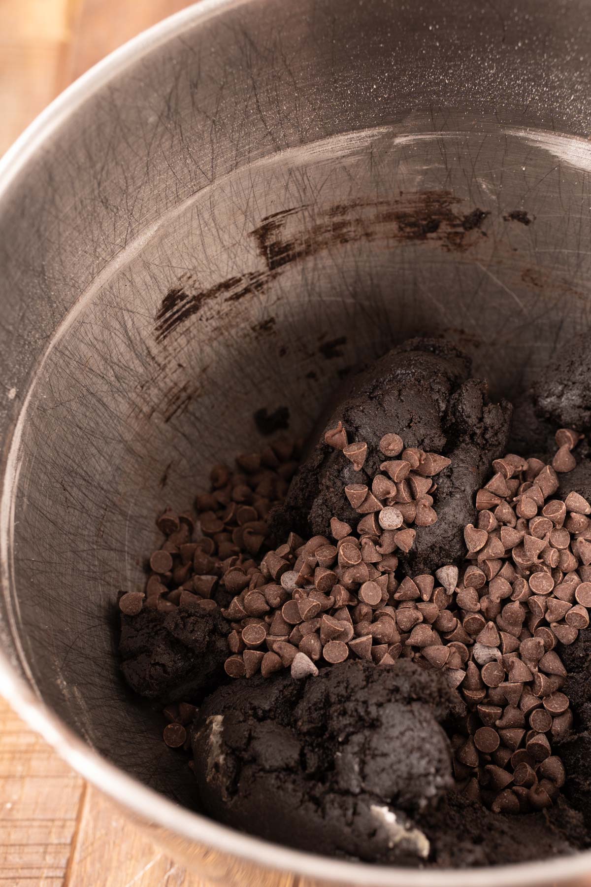 Chocolate chips being added to black cocoa cookie dough.