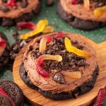 Big dirt cake cookies on a wooden board on a green surface.