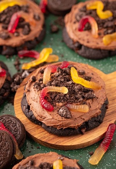 Big dirt cake cookies on a wooden board on a green surface.