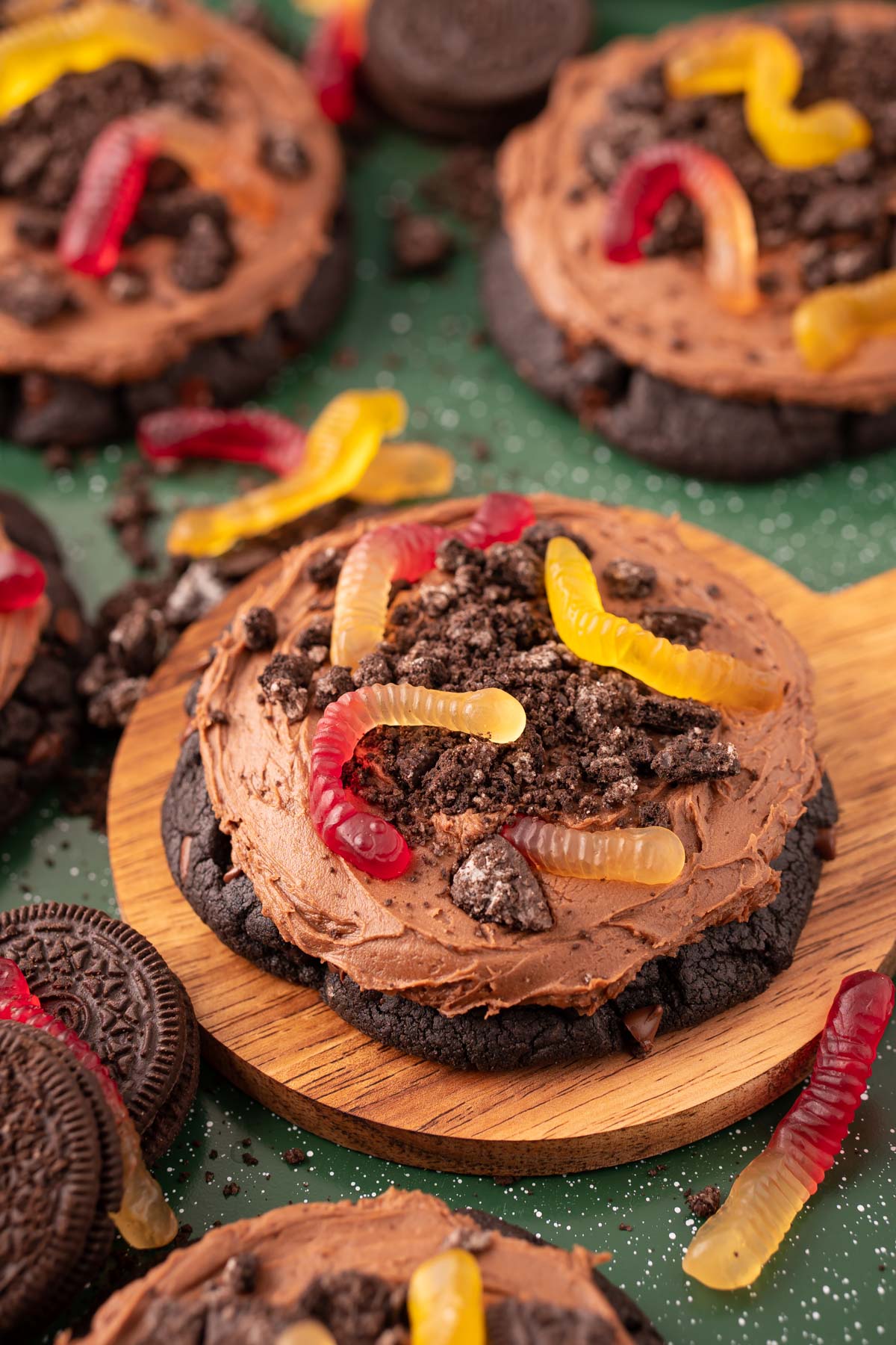 Big dirt cake cookies on a wooden board on a green surface.