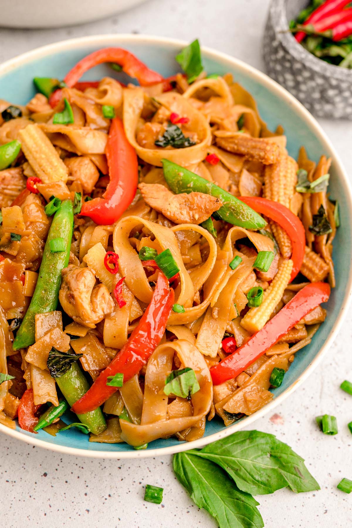 A blue bowl filled with drunken noodles.