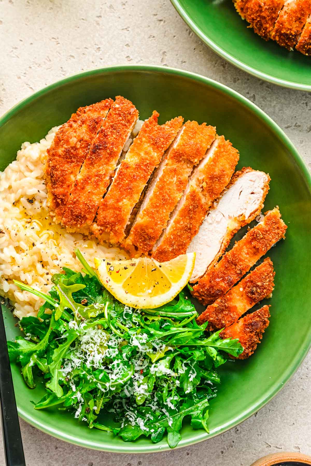 Overhead photo of panko breaded chicken in a green bowl with rice and greens.