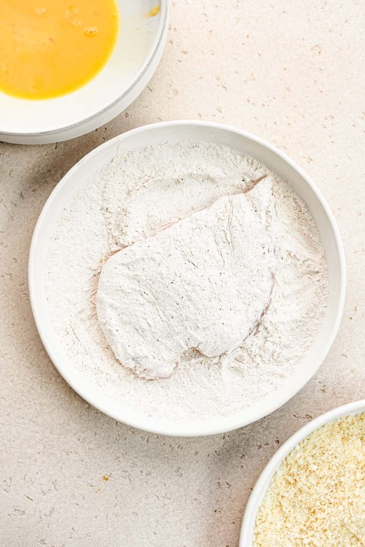 Chicken being dredged in flour.