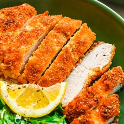 Overhead photo of panko chicken in a green bowl with rice and greens.