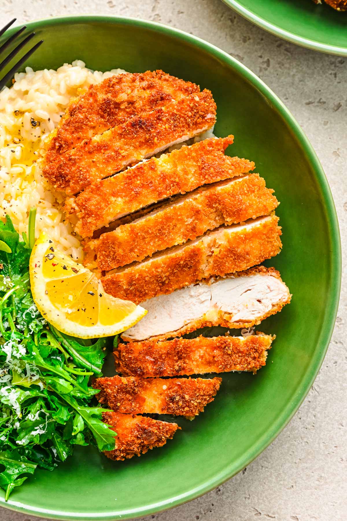 Overhead photo of panko chicken in a green bowl with rice and greens.
