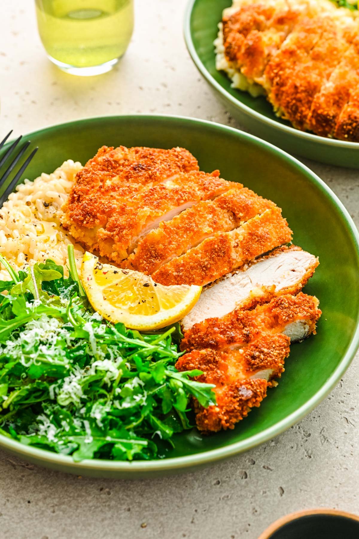 Panko crusted chicken in a green bowl with greens and rice.