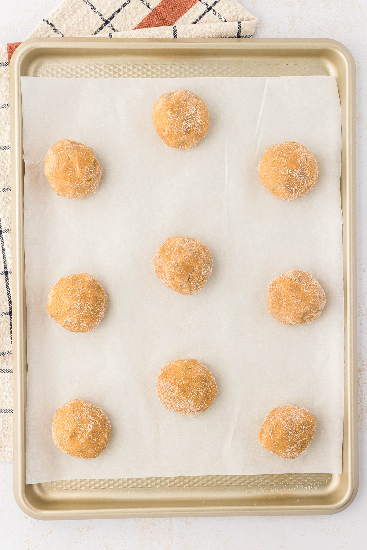Brown sugar cookie dough balls on a parchment lined baking sheet. 