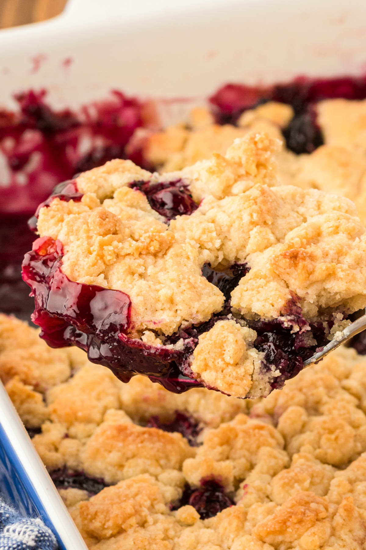 Blueberry cobbler being scooped out of a baking dish.