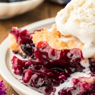 Close up of a serving of blueberry cobbler topped with vanilla ice cream.