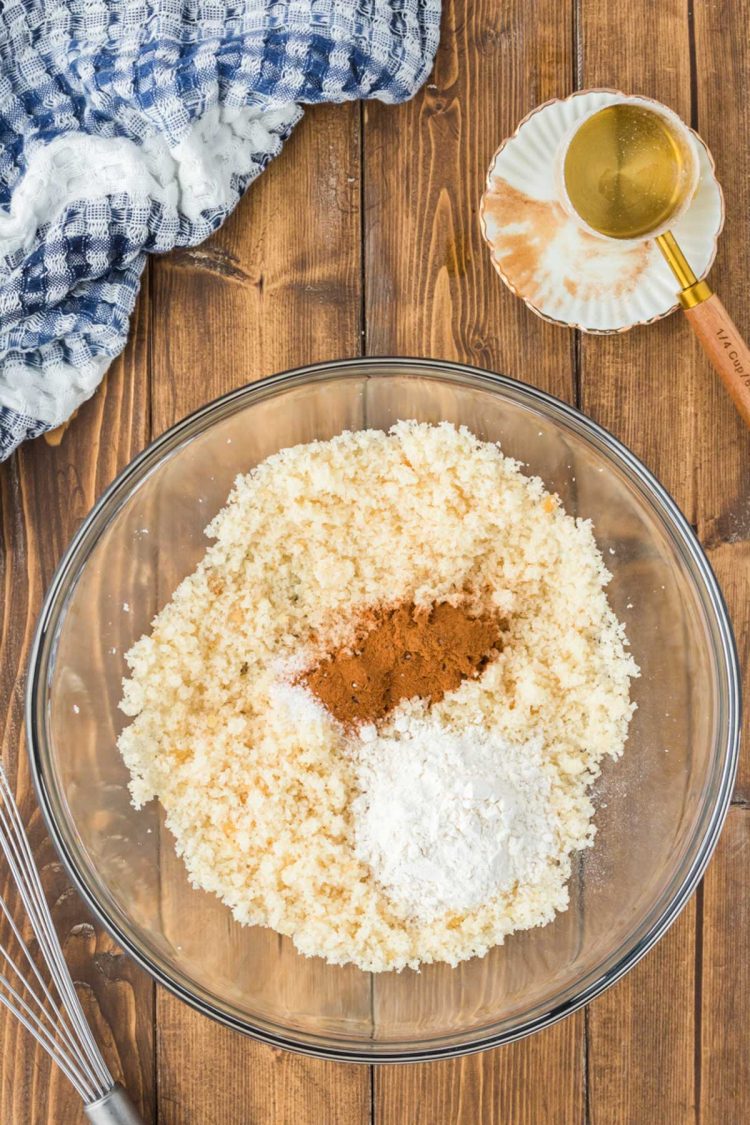 Baking ingredients being mixed together in a glass bowl on a wooden table.