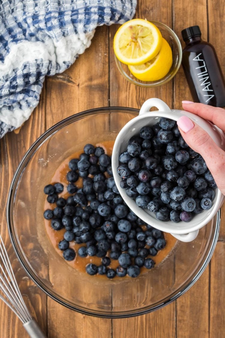 Blueberries being added to a bowl with butter, cinnamon, sugar, and more.