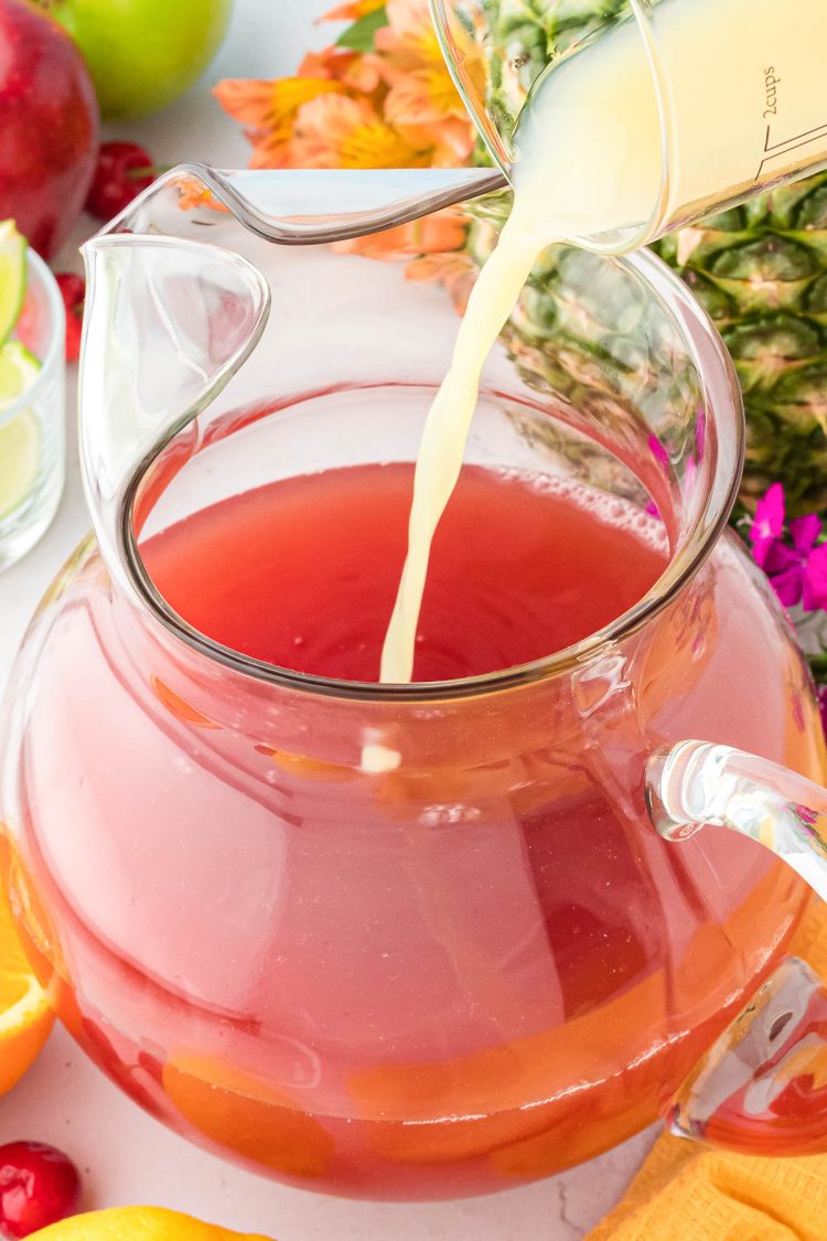 Lime juice being poured into a pitcher to make fruit punch.