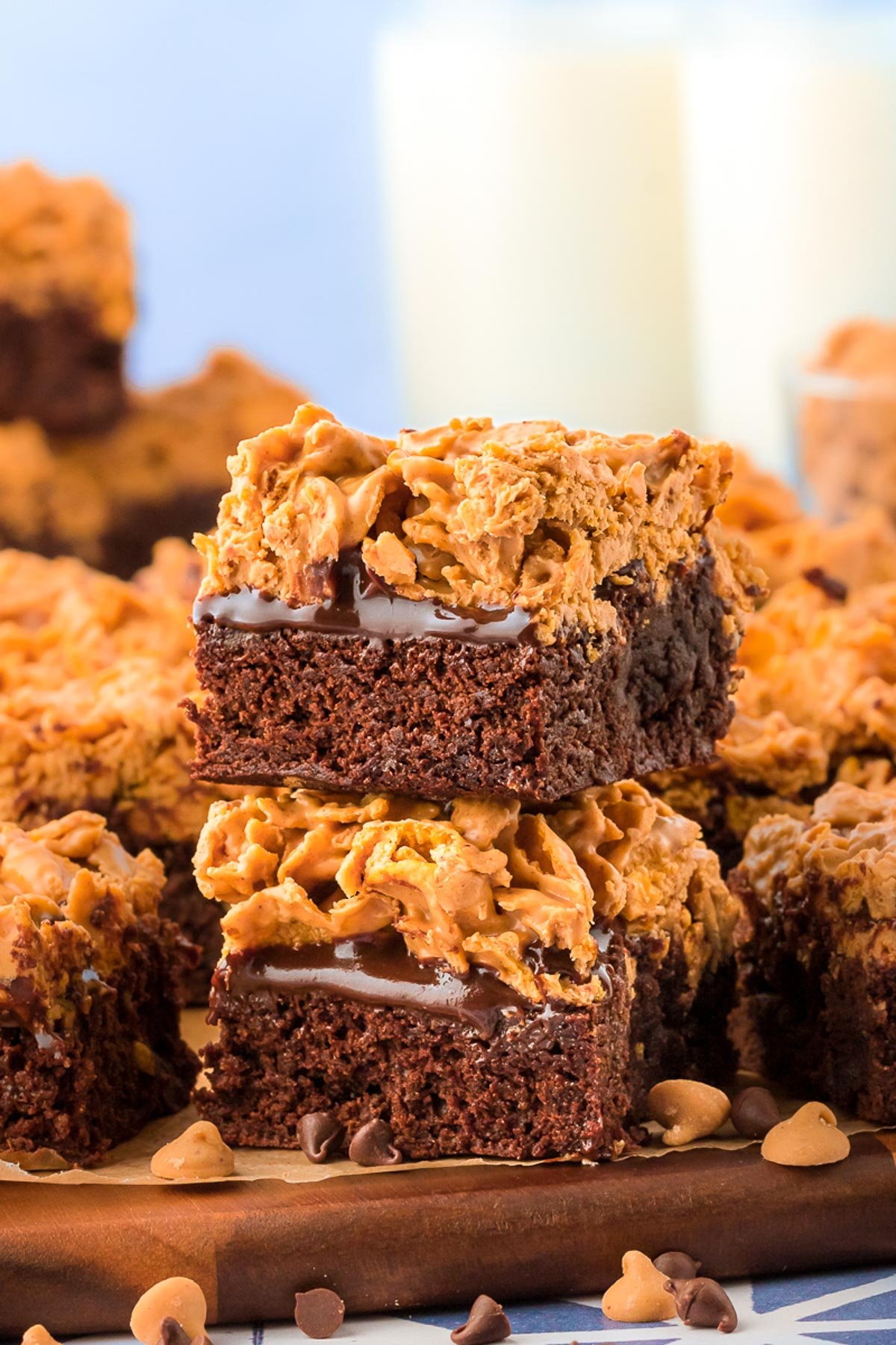 A stack of two peanut butter crunch brownies on a wooden plate with more in the background.