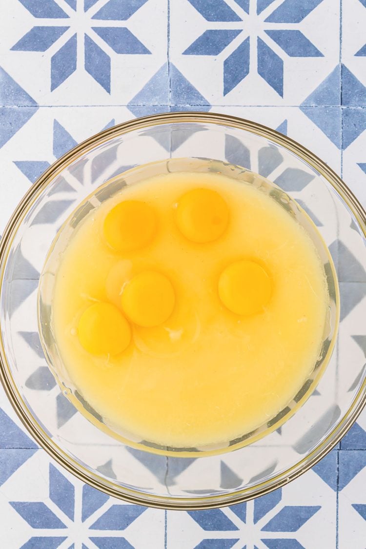 Eggs and oil being added to melted sugar and butter in a glass bowl.