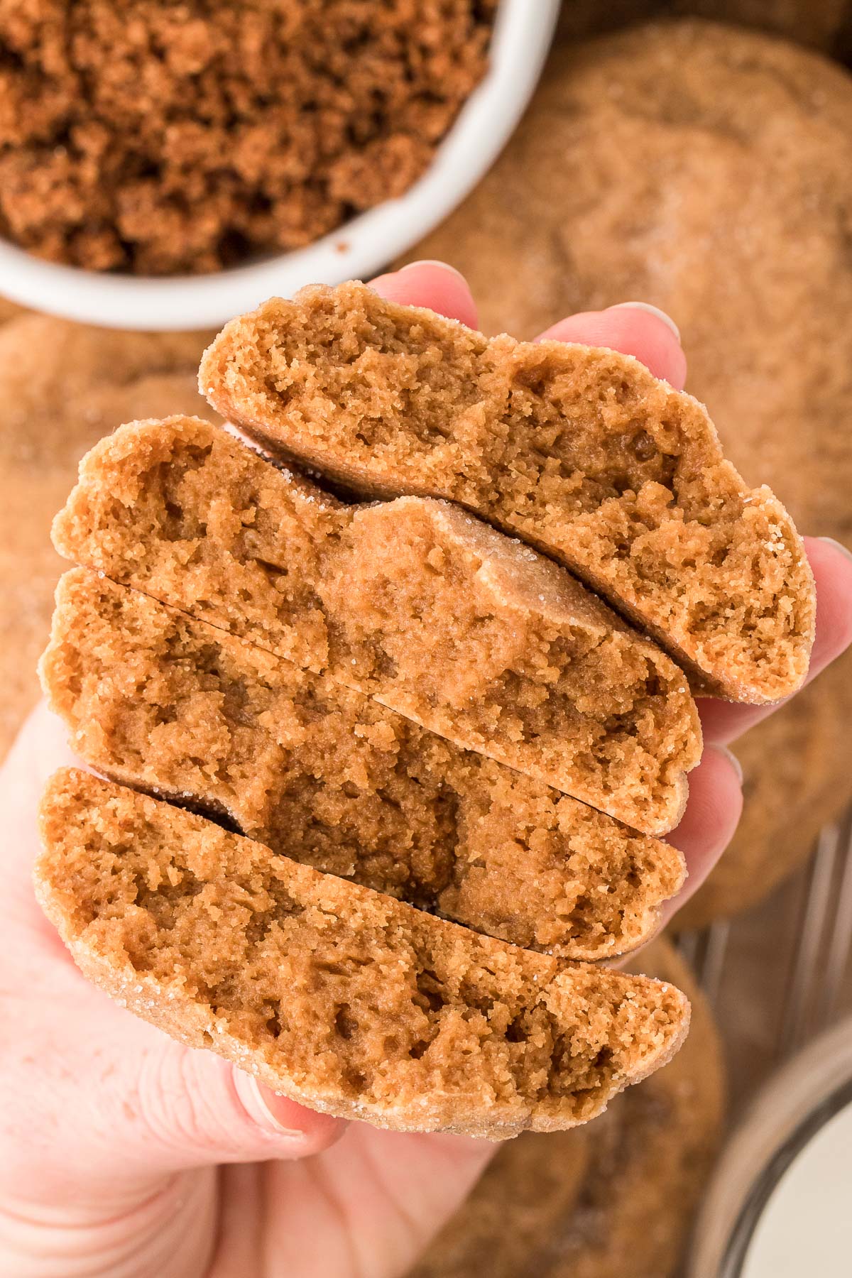 Brown sugar cookies broken in half to reveal soft centers in a woman's hand.