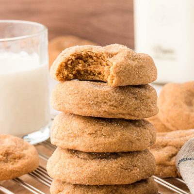 A stack of five brown sugar cookies, the top one is missing a bite.