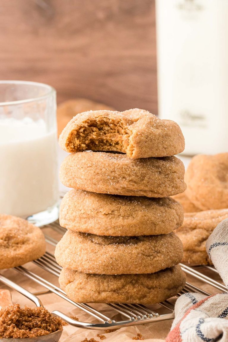 A stack of five brown sugar cookies, the top one is missing a bite.