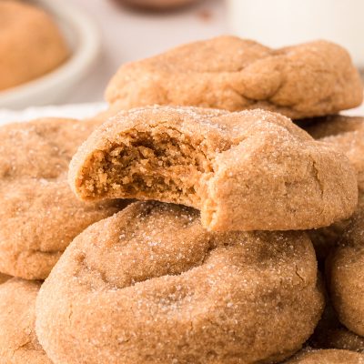 Soft brown sugar cookies on a pile on a plate, one cookie is missing a bite.