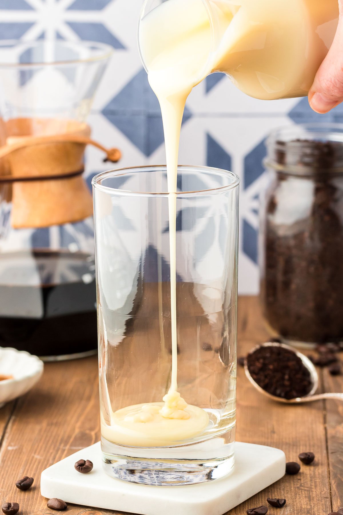 Sweetened condensed milk being poured into a tall glass.