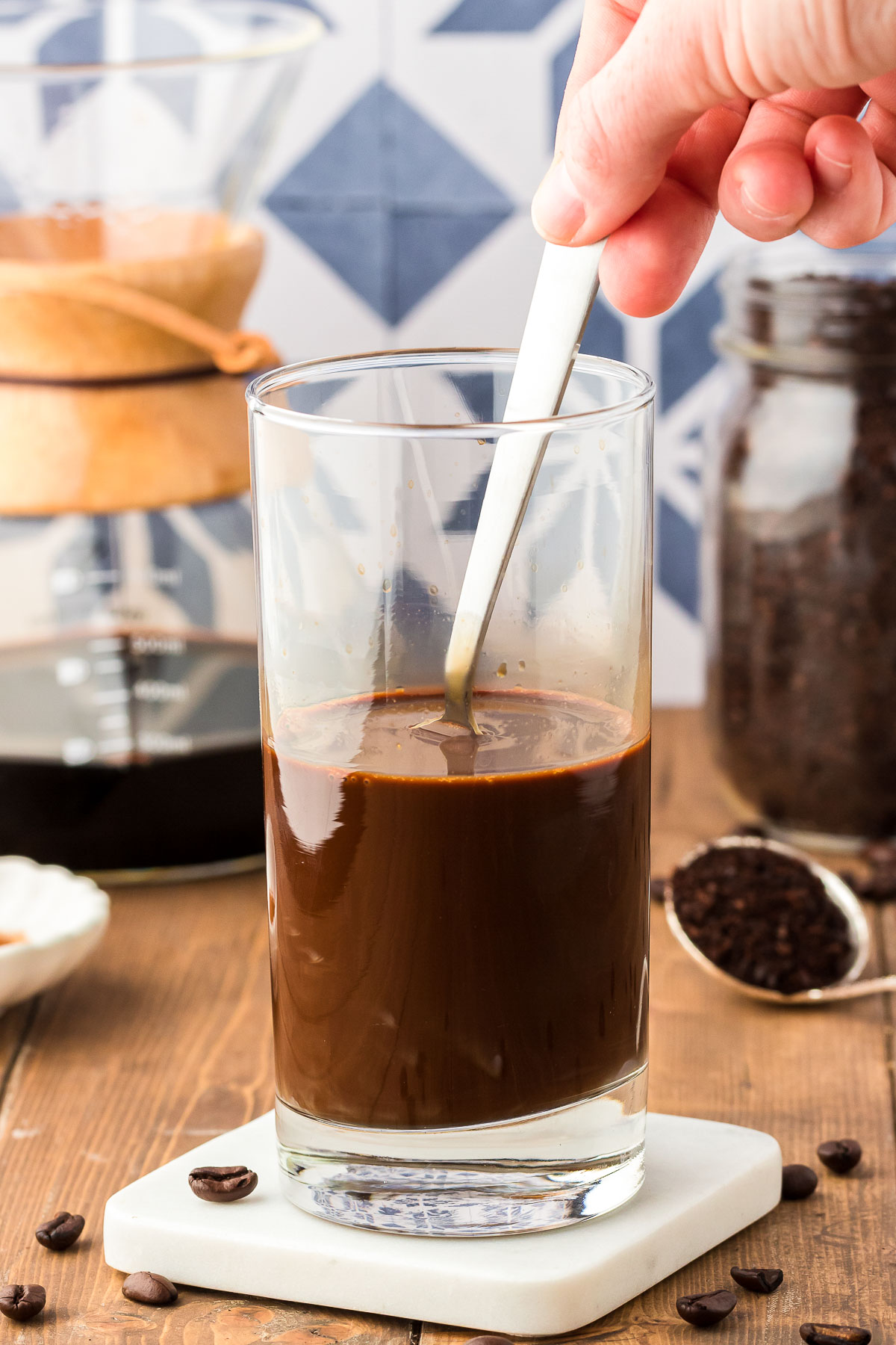 A spoon stirring thai coffee in a tall glass.