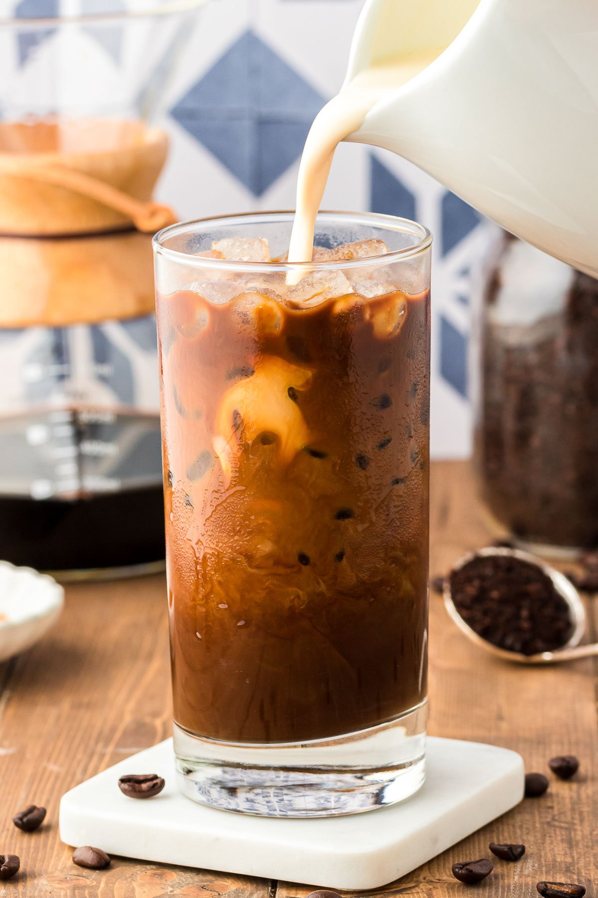 Cream being poured into a glass of Iced Thai Coffee.