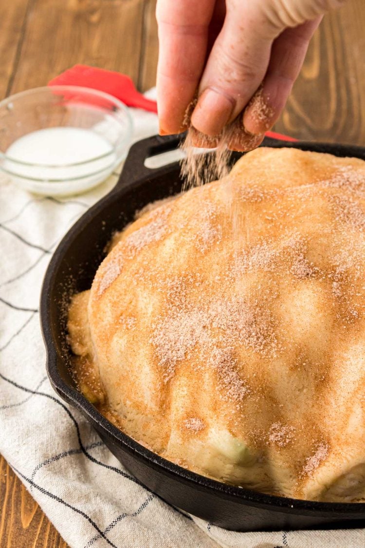 Cinnamon sugar being sprinkled over the top of pie crust.