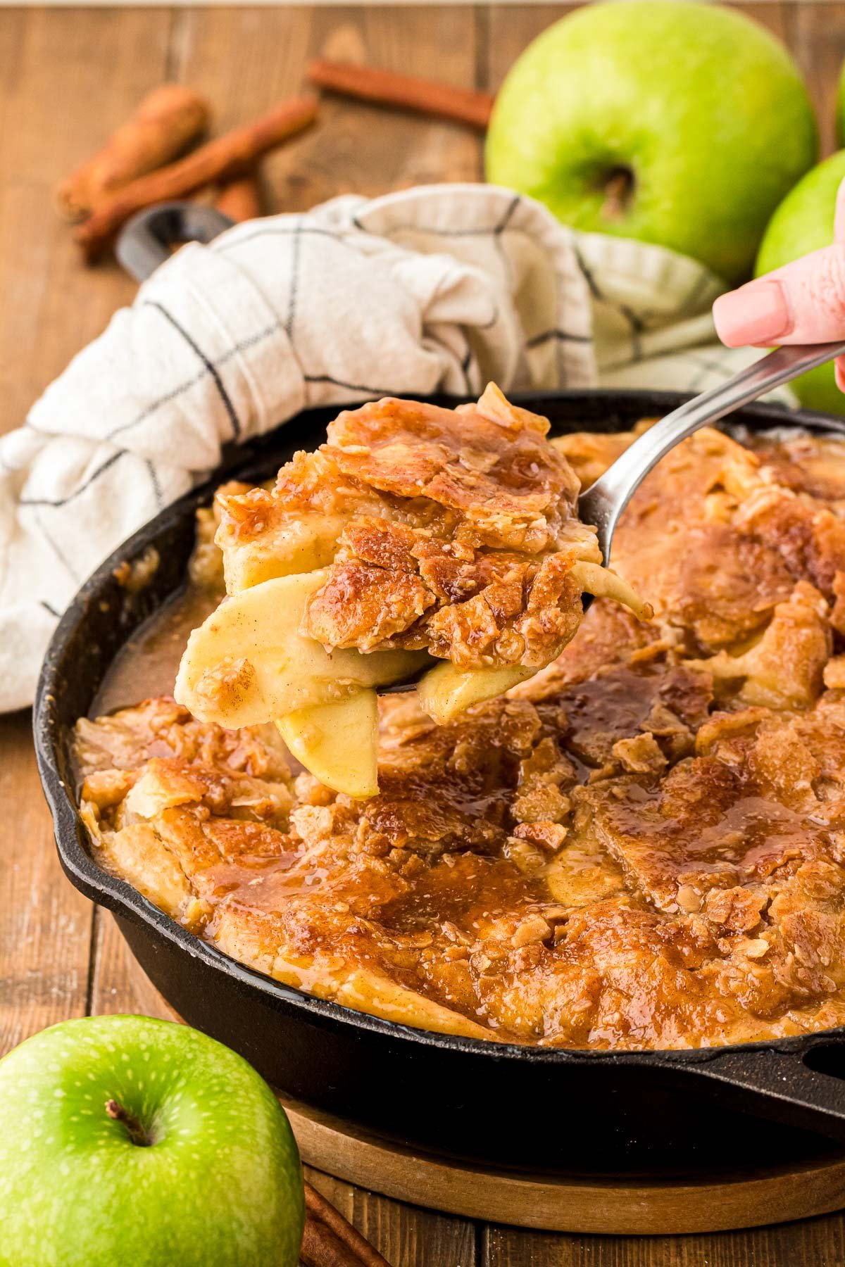 Apple pandowdy being scooped out of a skillet.