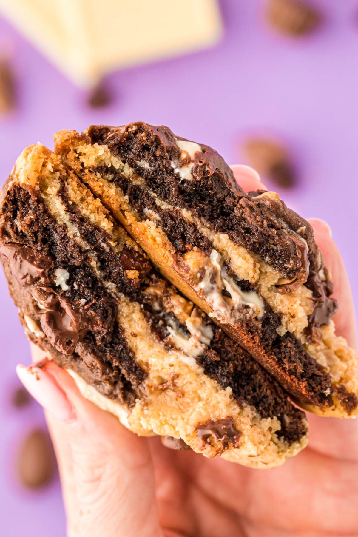 A woman's hand holding a kitchen sink cookie that's been cut in half.