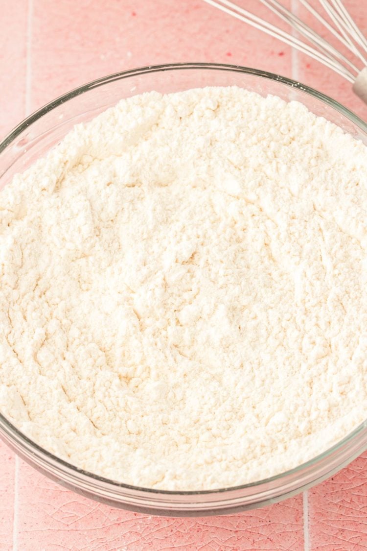 Flour and other drying ingredients whisked in a glass bowl.