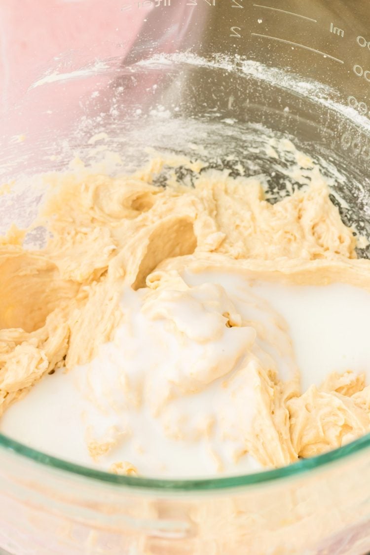 Milk being added to a bowl of cake batter.