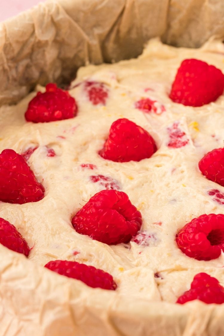 Raspberries pressed into the top of cake batter in a pan.