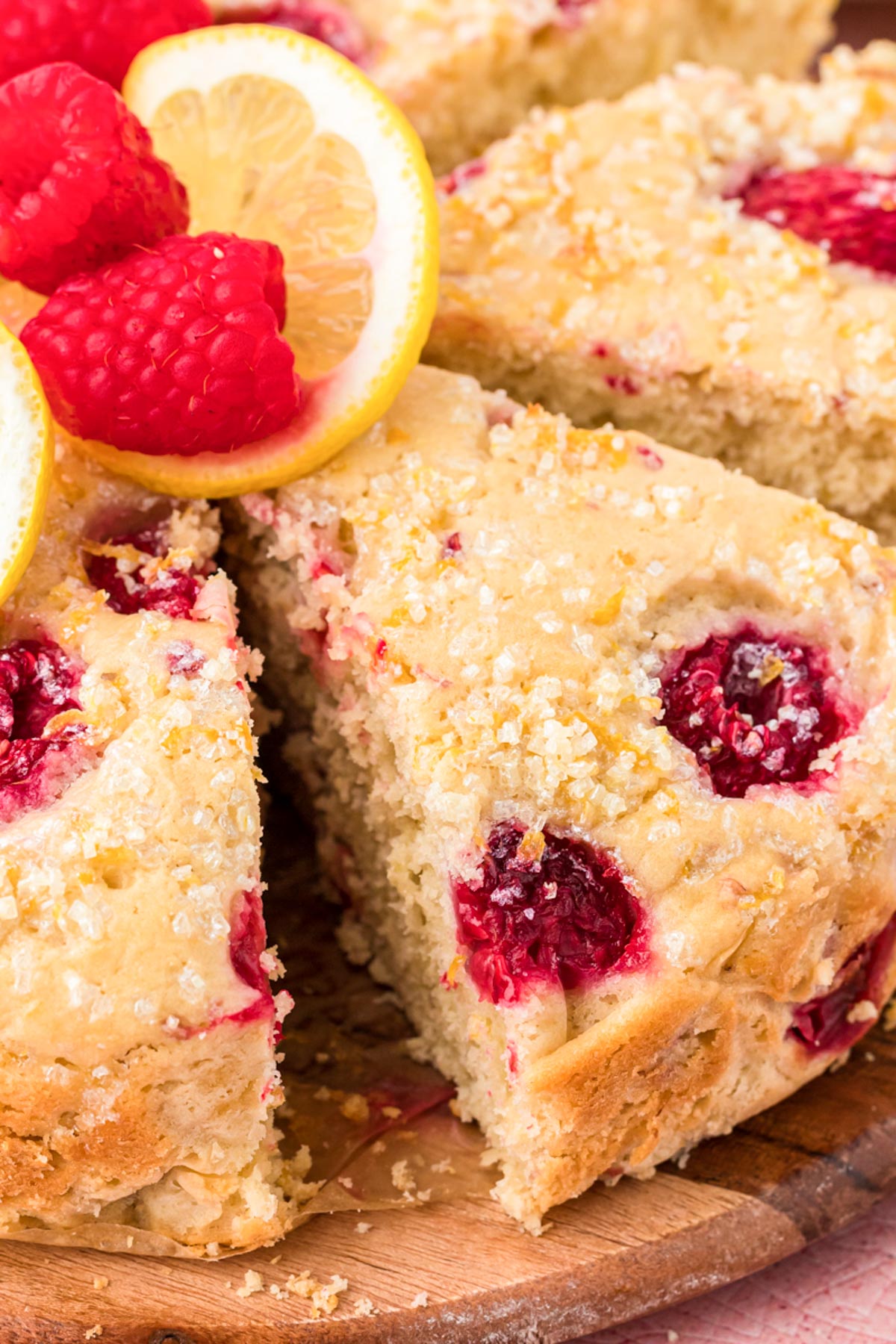 Raspberry lemon cake on a wooden serving board.