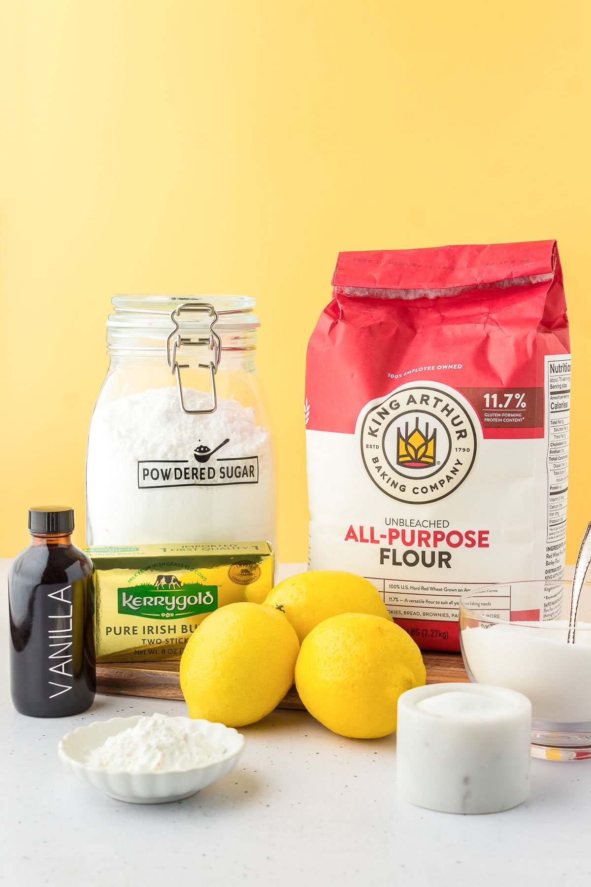 Ingredients to make lemon shortbread on a white table.