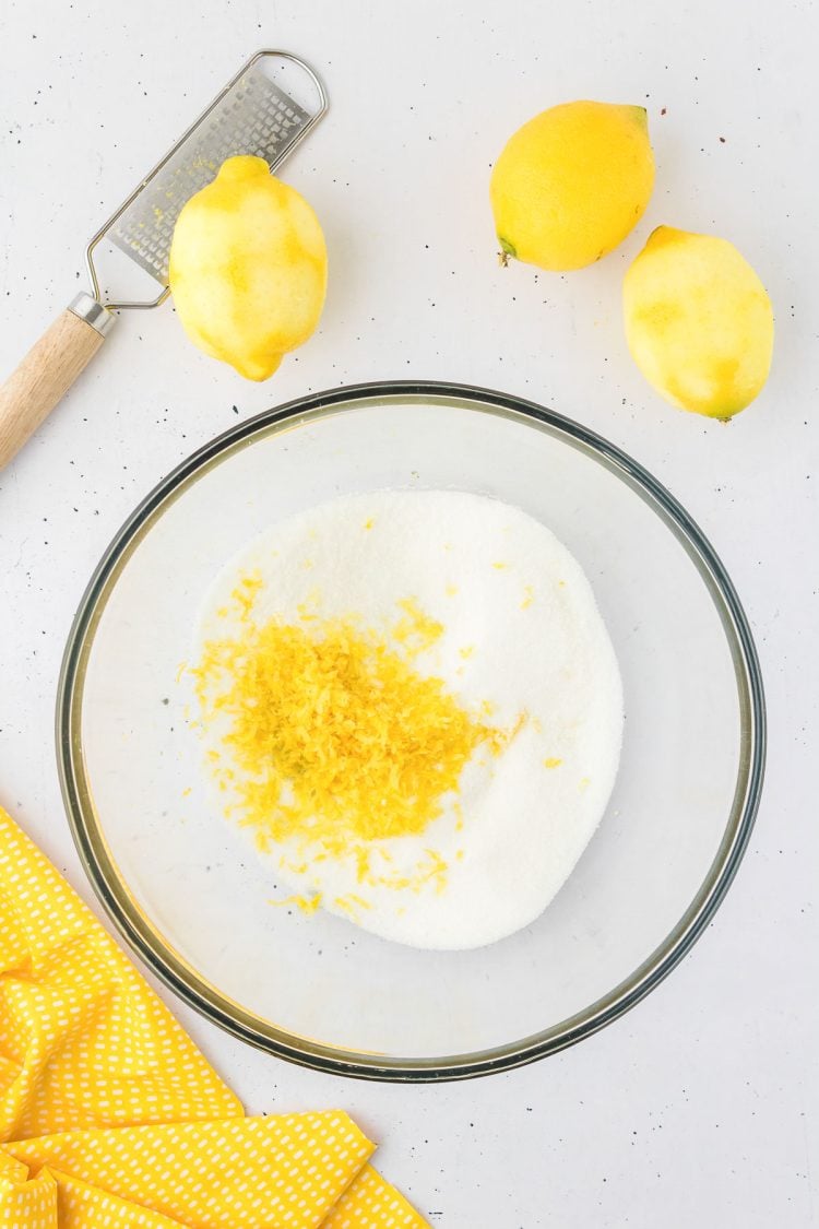 Sugar and lemon zest in a large glass mixing bowl.